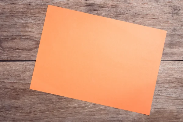 Empty orange paper on wooden table top view — Stock Photo, Image