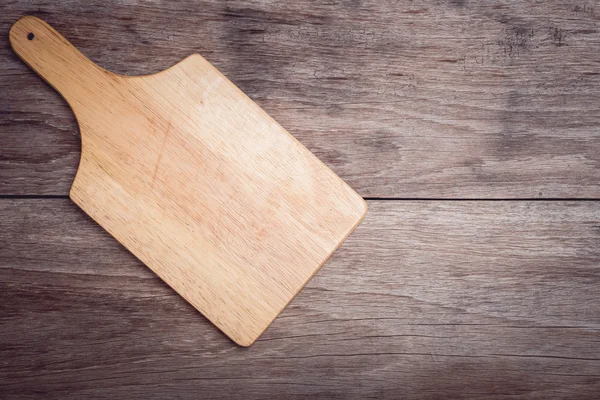 Wooden chopping board on wooden table top view