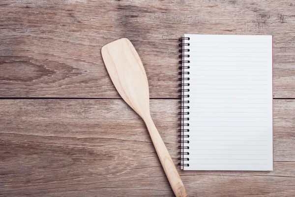 Cooking wooden spatula and lined paper on wooden table top view — Stock Photo, Image