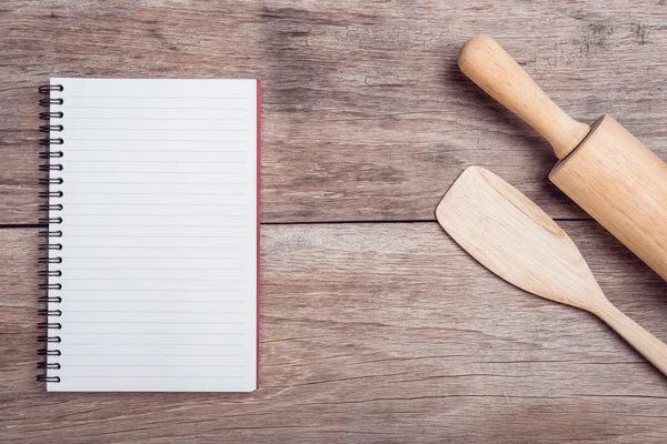 Cooking wooden spatula, rolling pin and lined paper on wooden ta — Stock Photo, Image