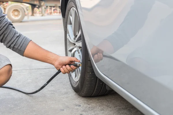 Man checking air pressure and filling air to the tires of his ca — Stock Photo, Image