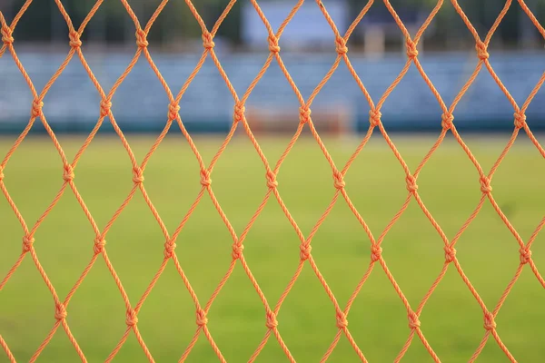 Turuncu futbol yeşil çim zemin üzerine net — Stok fotoğraf