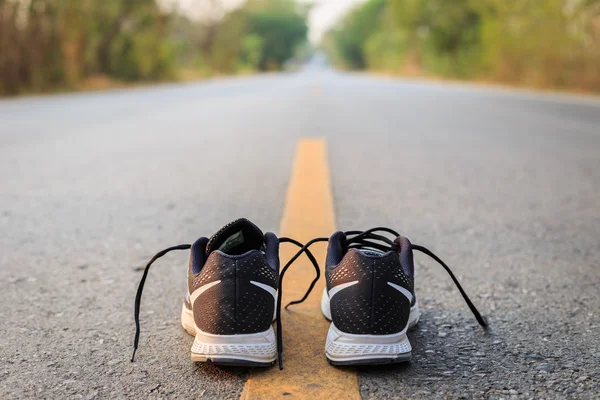 New black running shoes on asphalt road in morning time