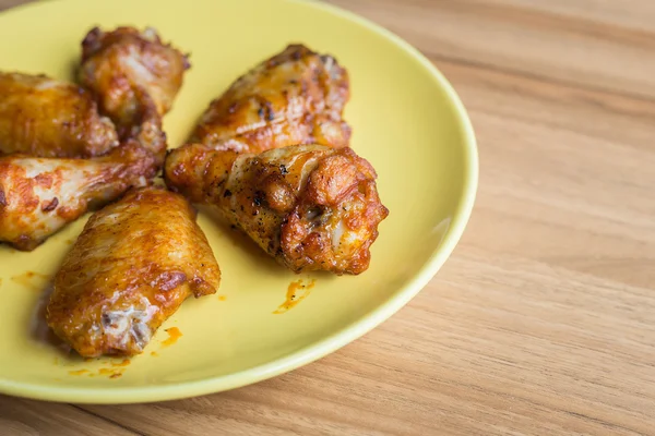 Asas de frango fritas em prato verde na mesa de madeira — Fotografia de Stock