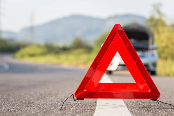 Czerwony awaryjny znak stopu i zepsuty samochód na drodze — Zdjęcie stockowe