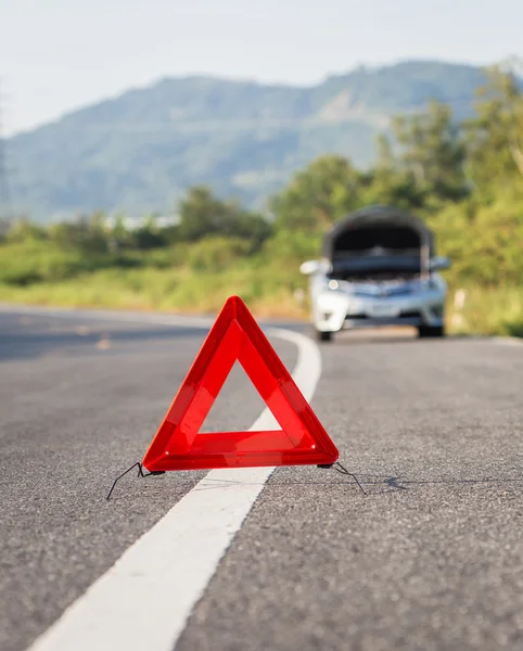 Señal roja de parada de emergencia y coche roto en la carretera — Foto de Stock