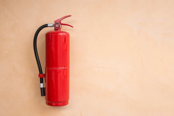Red fire extinguisher tank på orange vägg — Stockfoto