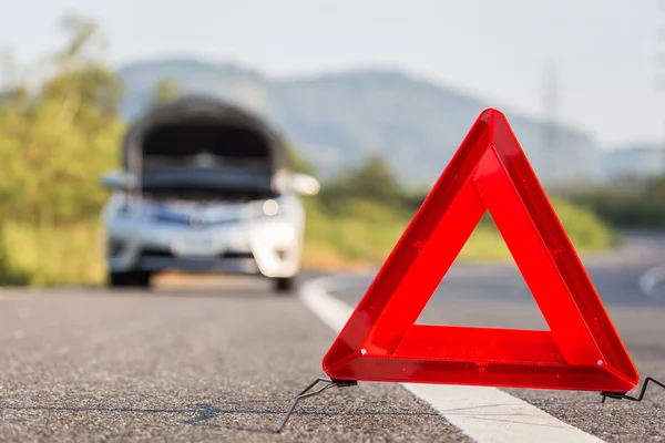 Червоний знак аварійної зупинки і зламаний автомобіль на дорозі — стокове фото