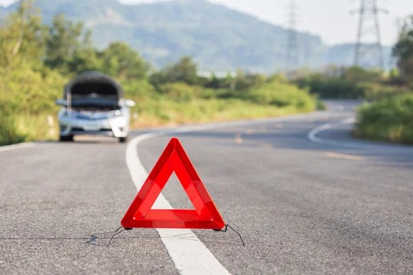 Señal roja de parada de emergencia y coche roto en la carretera — Foto de Stock