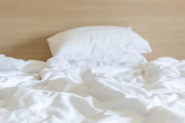 Sábanas blancas y almohada, concepto de cama desordenado — Foto de Stock