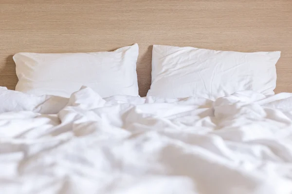 Sábanas blancas y almohada, concepto de cama desordenado —  Fotos de Stock