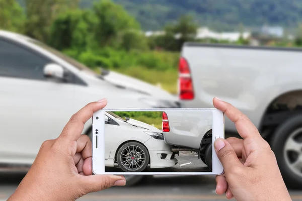 Mão de mulher segurando smartphone e tirar foto de acidente de carro — Fotografia de Stock