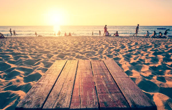 顶部的木头桌子前日落海滩与镜头光晕。温暖的色调 — 图库照片