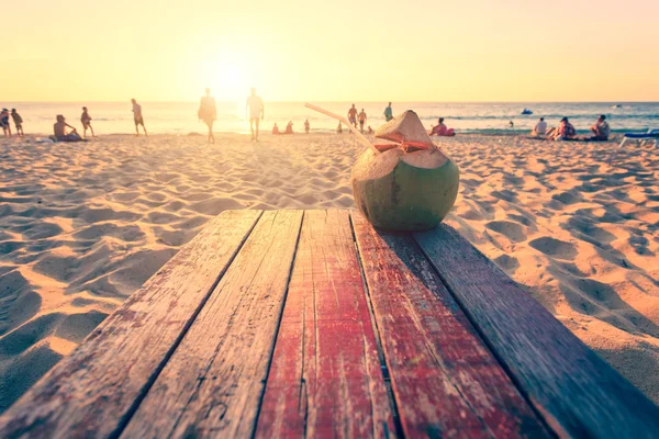 Coconut on top of wooden table at sunset beach in Thailand with — Stock Photo, Image