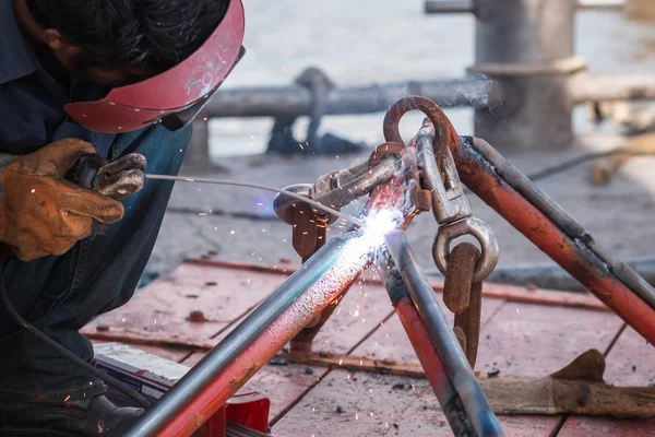 Man welding steel on the part of fishing boat at the harbor — Stock Photo, Image