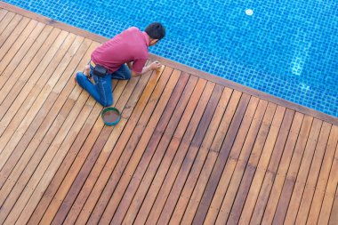 A man painting exterior wooden pool deck, Top view clipart