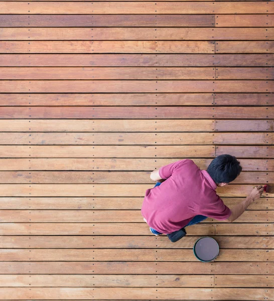 A man painting exterior wooden pool deck, Top view