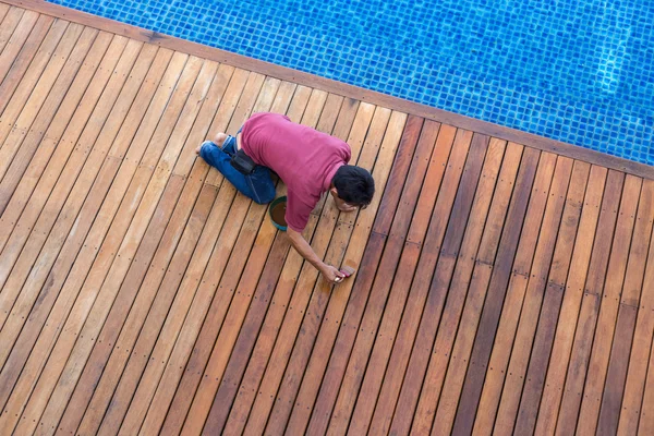 Bir adam boyama dış ahşap havuz güvertesi, üstten görünüm