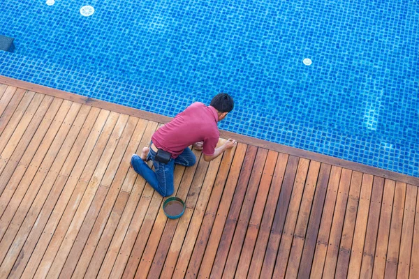 Un hombre pintando exterior piscina de madera cubierta, vista superior — Foto de Stock