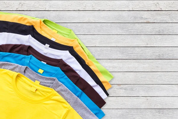 Bovenaanzicht van kleur T-Shirt op houten achtergrond — Stockfoto