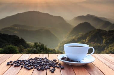 Beyaz kahve fincanı ve ahşap masa üzerinde kahve çekirdekleri kapatın ve vie