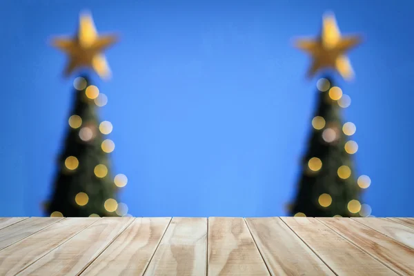 Table en bois vide et arbre de Noël flou sur fond bleu ciel — Photo