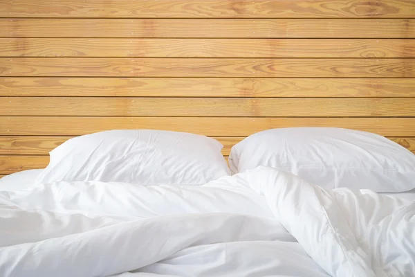 Белые простыни и подушки на фоне деревянной стены комнате , — стоковое фото
