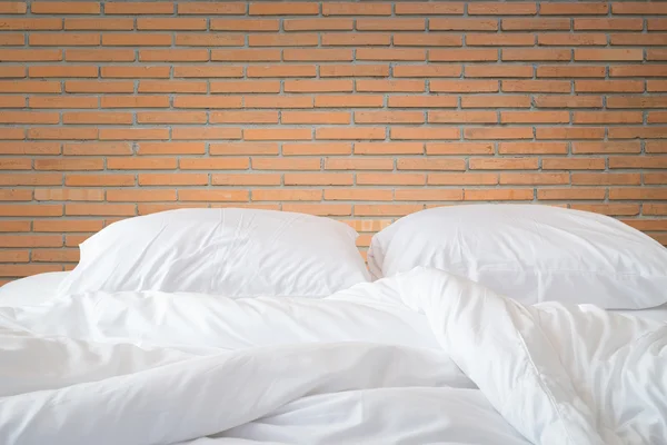 Sábanas blancas y almohada en la pared de piedra natural habitación trasera —  Fotos de Stock