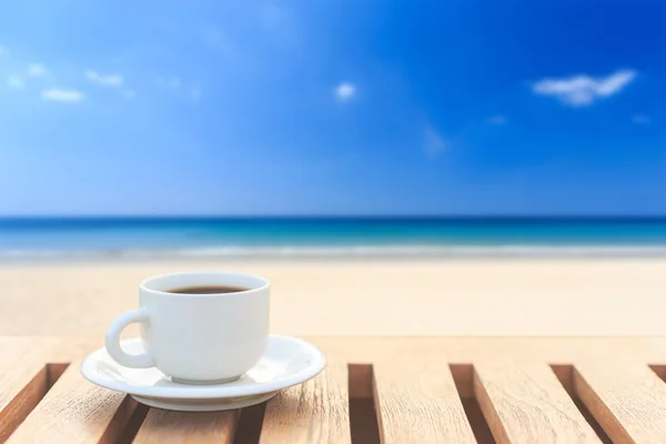 Taza de café sobre mesa de madera y vista de la playa tropical —  Fotos de Stock