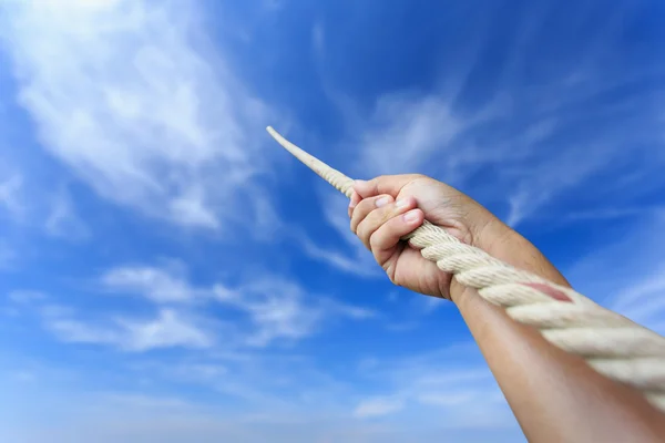 Close up hand holding rope on blur sky — Stock Photo, Image