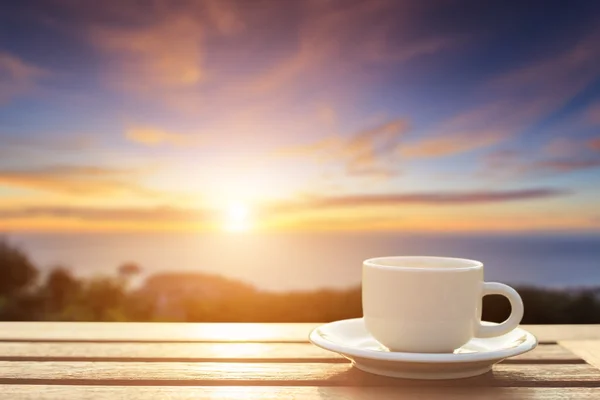 Coffee cup on wood table at sunset or sunrise time — Stock Photo, Image