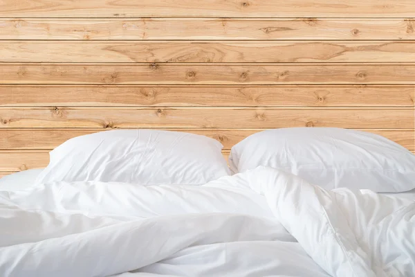 Sábanas blancas y almohada sobre fondo de pared de madera , — Foto de Stock