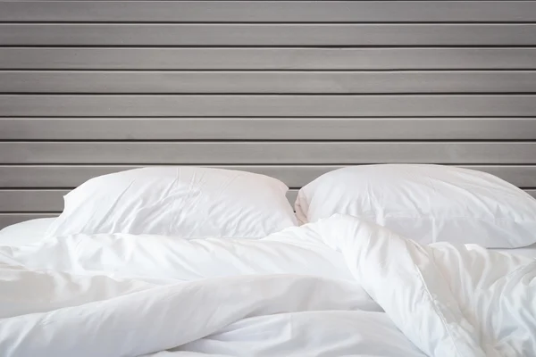 Белые простыни и подушки на фоне деревянной стены комнате , — стоковое фото