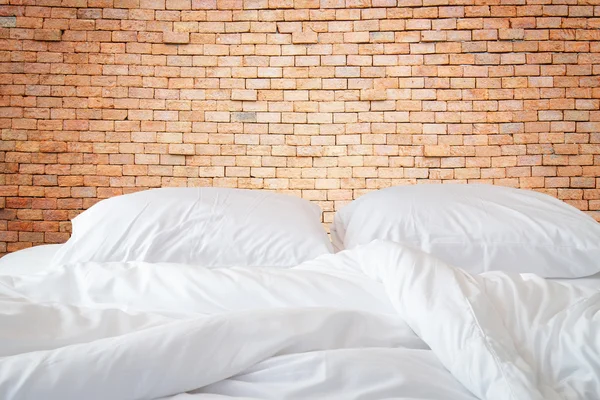 Lençóis brancos e travesseiro na parede de pedra natural backg quarto — Fotografia de Stock