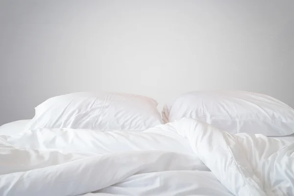 Sábanas blancas y almohada en la pared de piedra natural habitación trasera —  Fotos de Stock