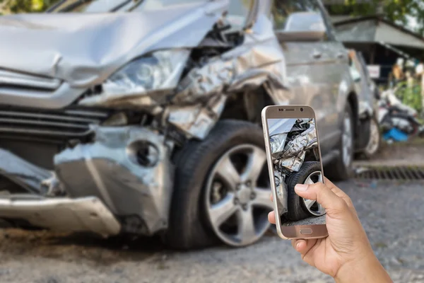 Mano de la mujer sosteniendo el teléfono inteligente y tomar una foto del accidente de coche — Foto de Stock