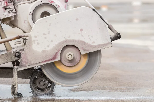 Worker cutting concrete road with diamond saw blade machine