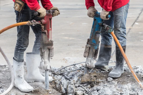 Byggeri arbejdstager fjerner overskydende beton med boremaskine - Stock-foto