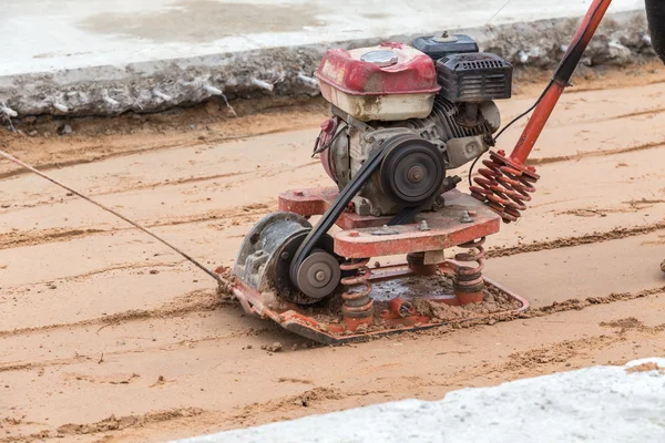 Trabajador con compactadores de suelo rojo en obra — Foto de Stock