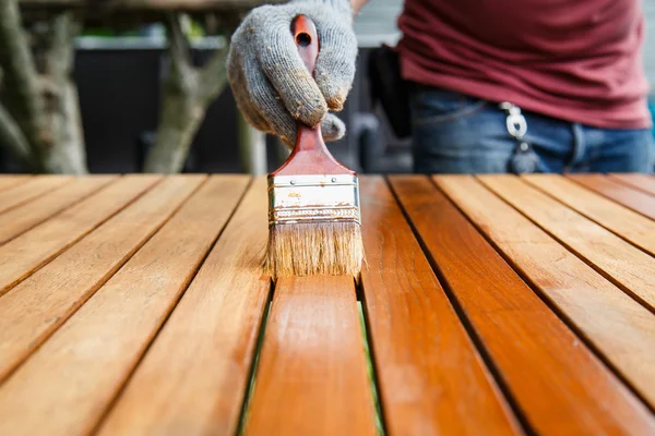 Brush in hand and painting on the wooden table — Stock Photo, Image