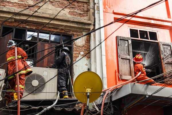 Bombeiro usando mangueira de água para prevenir o fogo — Fotografia de Stock