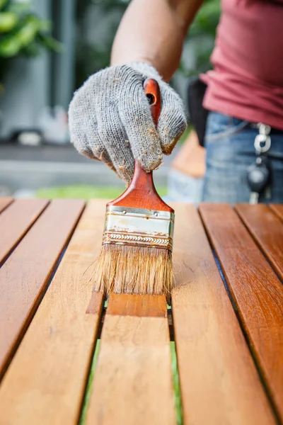 Pincel na mão e pintura na mesa de madeira — Fotografia de Stock