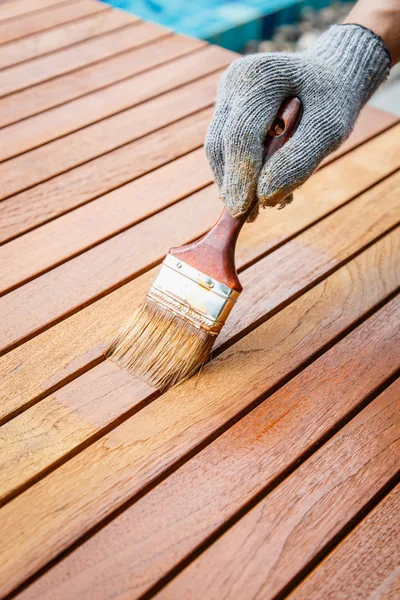 Penseel in de hand en schilderij op houten tafel — Stockfoto