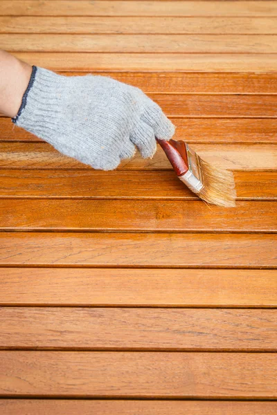 Pincel en mano y pintura sobre la mesa de madera — Foto de Stock