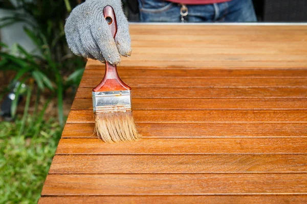 Pincel en mano y pintura sobre la mesa de madera — Foto de Stock