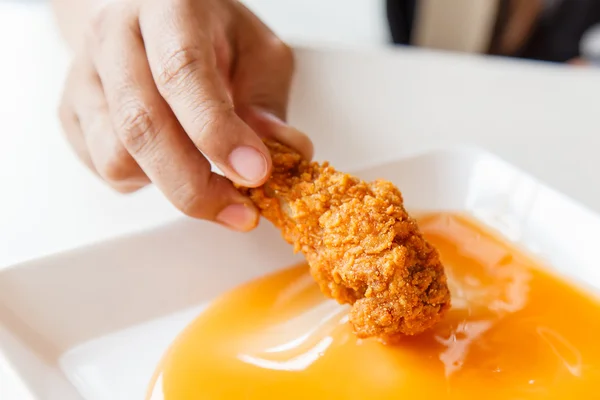 Ruka držící Fried chicken a jíst v restauraci — Stock fotografie