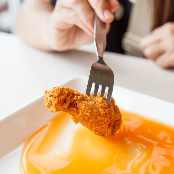 Ręką trzyma smażony kurczak i jedzenie w restauracji — Zdjęcie stockowe