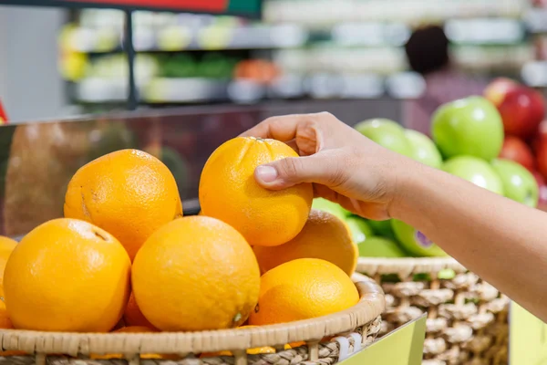 Рука держит апельсин в магазине — стоковое фото