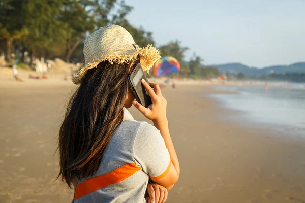 समुद्र तट पर स्मार्टफ़ोन का उपयोग करने वाली थाई महिला — स्टॉक फ़ोटो, इमेज
