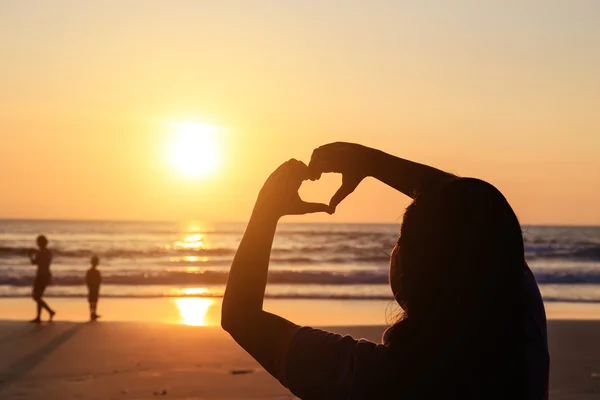 Silueta de manos en símbolo del corazón alrededor del sol — Foto de Stock
